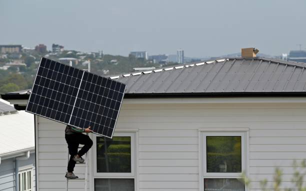 Solar installer carrying a panel up to the roof of an Australian home during a residential solar installation